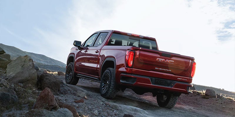 A red GMC Sierra Climbing a rough road rear view
