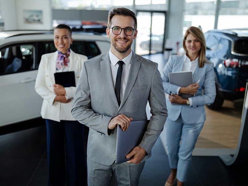 A team of employees stands with laptops